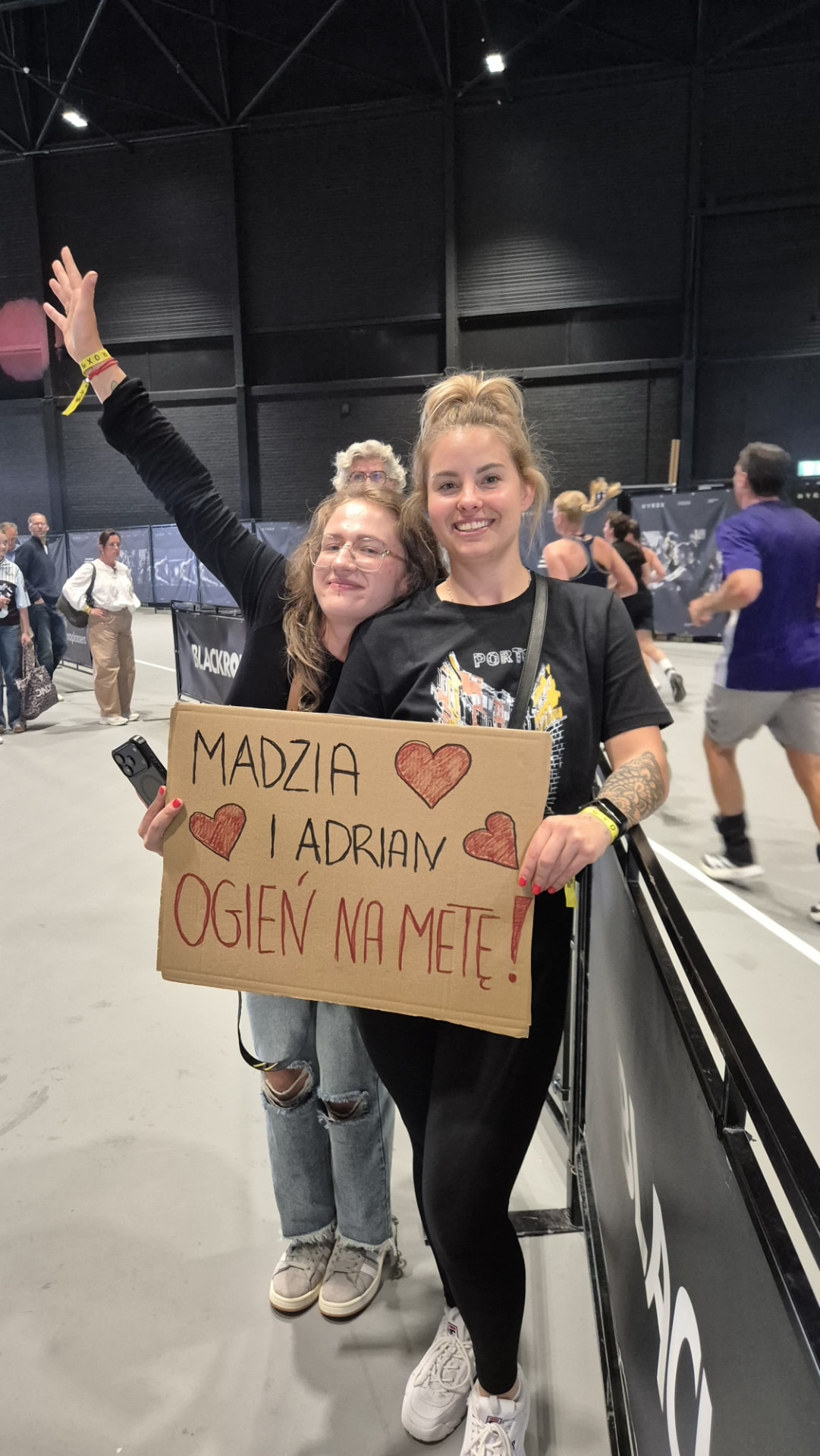 Supporters cheering with a handmade sign at a HYROX event