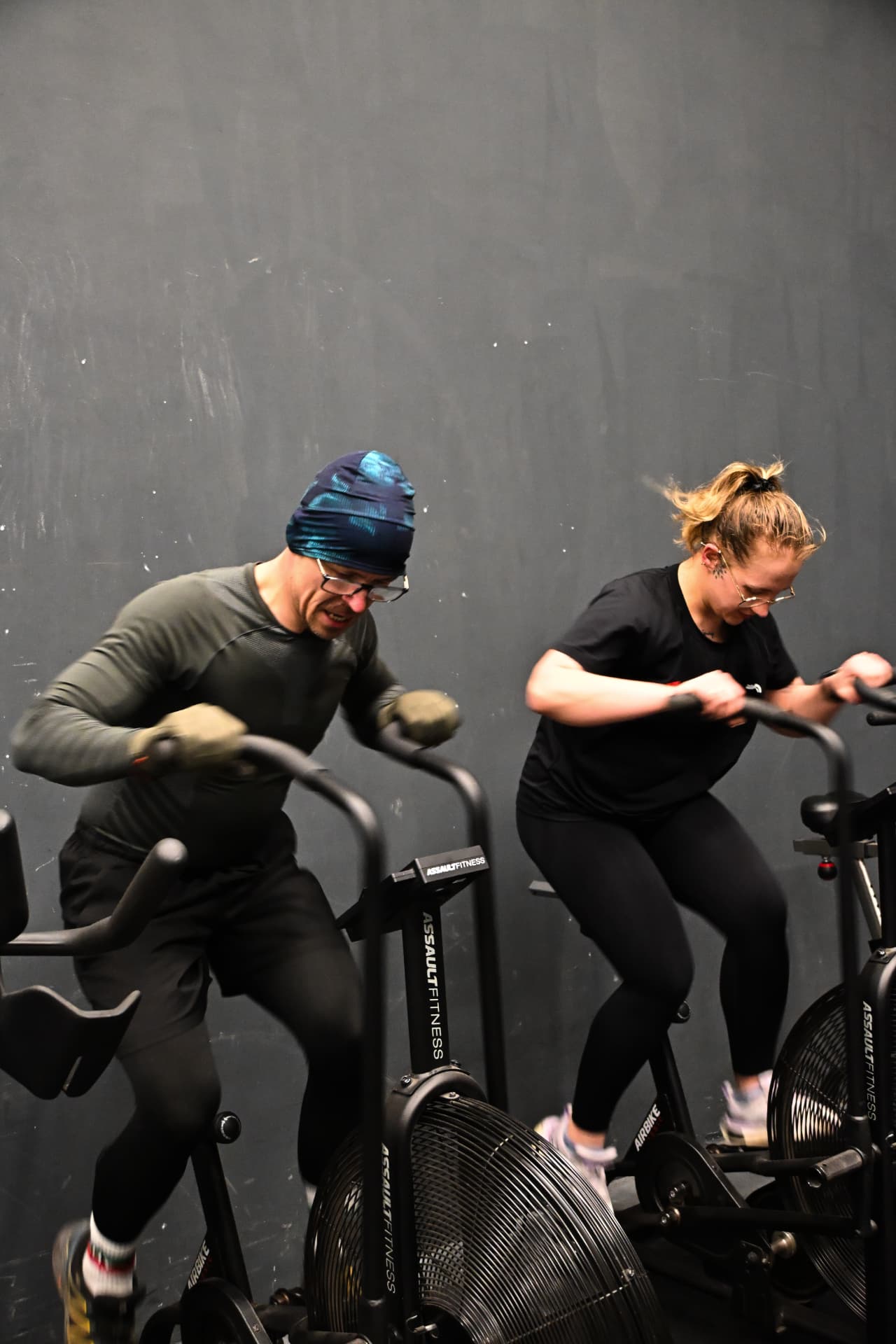 Pair training hard on AirBikes in the gym