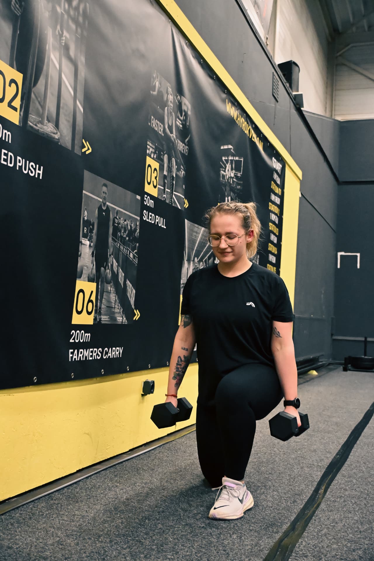 Athlete doing weighted lunges at a HYROX station